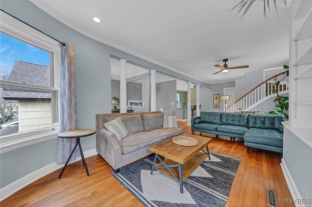 living room featuring wood-type flooring, stairs, a ceiling fan, and baseboards