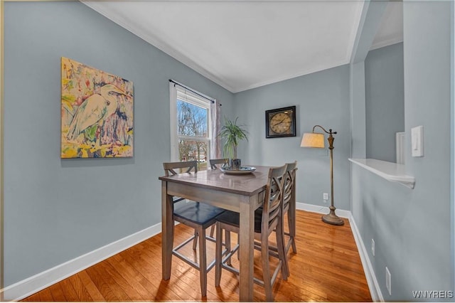 dining space featuring wood finished floors, baseboards, and ornamental molding