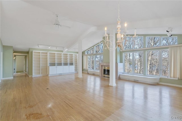 3158 W Lake Rd, Cazenovia, NY 13035 - unfurnished living room with ceiling fan with notable chandelier, a fireplace with flush hearth, vaulted ceiling, wood finished floors, and baseboards