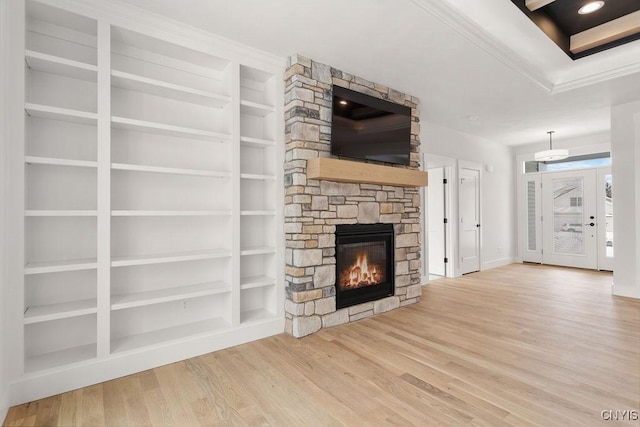 unfurnished living room with crown molding, a fireplace, built in features, baseboards, and wood finished floors