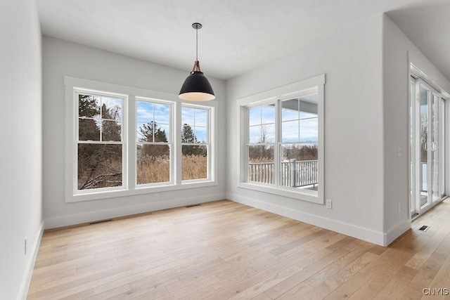 unfurnished dining area with baseboards, light wood finished floors, and visible vents