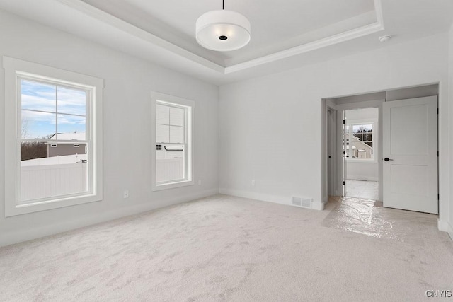 unfurnished room with carpet floors, crown molding, visible vents, and a raised ceiling