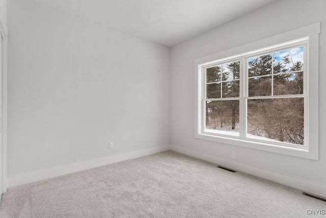 carpeted empty room featuring baseboards and visible vents