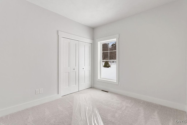 unfurnished bedroom featuring visible vents, carpet flooring, baseboards, and a closet