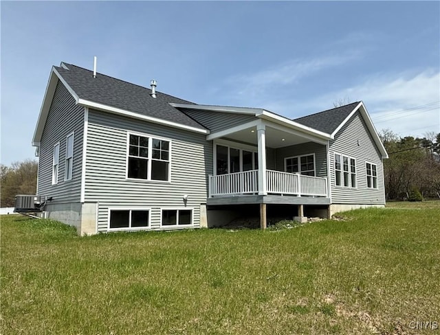 back of house with a lawn, cooling unit, and roof with shingles