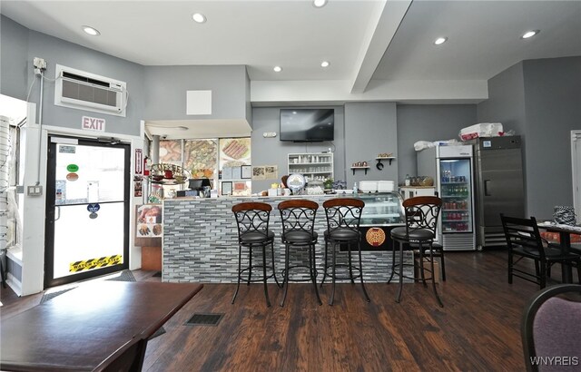 894 Tonawanda St, Buffalo, NY 14207 - bar with visible vents, recessed lighting, wood finished floors, an AC wall unit, and stainless steel built in fridge