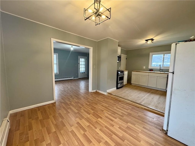 kitchen with white cabinets, a baseboard radiator, light wood finished floors, and stainless steel appliances