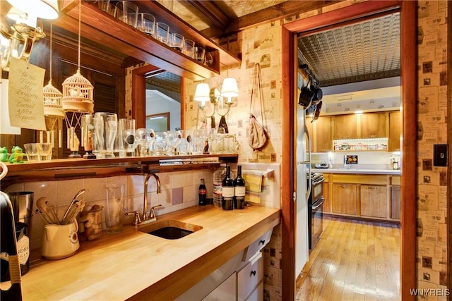 6634 Lake Shore Rd, Evans, NY 14047 - indoor wet bar featuring light wood-style flooring, hanging light fixtures, range with two ovens, and wallpapered walls