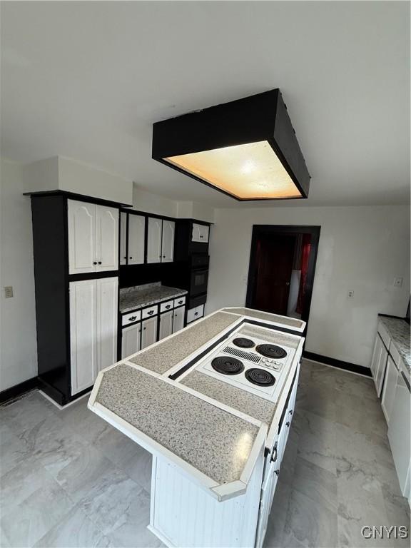 620 Court St, Syracuse, NY 13208 - kitchen featuring a center island, baseboards, oven, white electric stovetop, and marble finish floor