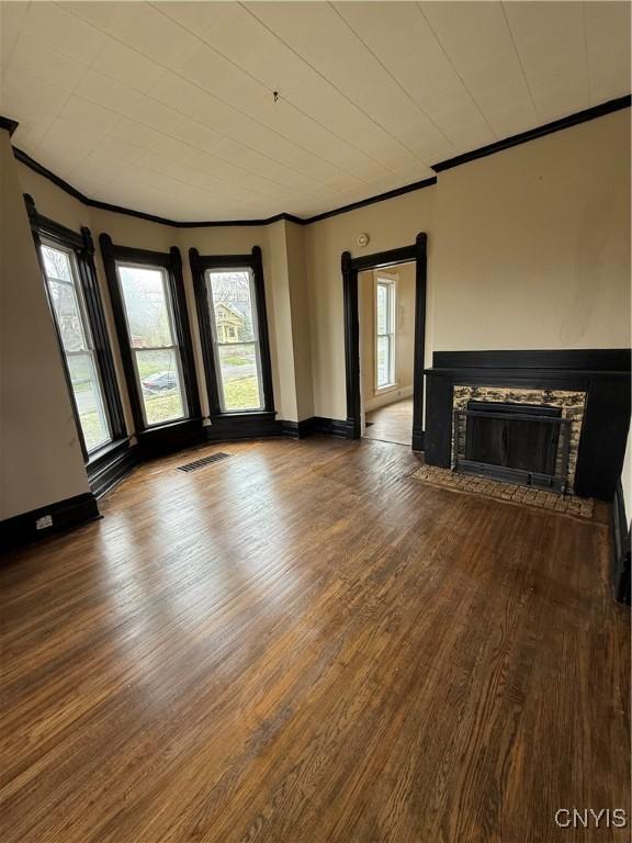 620 Court St, Syracuse, NY 13208 - unfurnished living room with visible vents, baseboards, a fireplace, crown molding, and wood finished floors