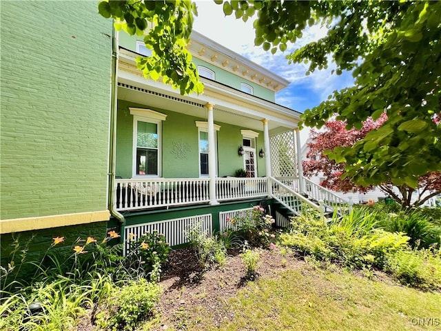 exterior space with covered porch and brick siding