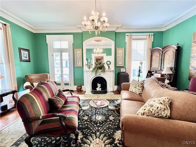 living room with crown molding, an inviting chandelier, a fireplace, wood finished floors, and baseboards
