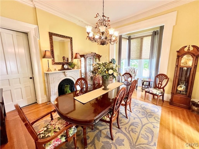 dining room with baseboards, an inviting chandelier, a fireplace, crown molding, and wood finished floors