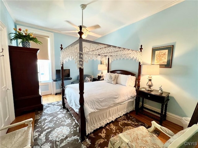 bedroom featuring crown molding, baseboards, a ceiling fan, and wood finished floors