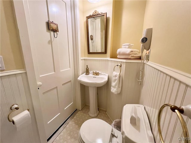 bathroom with tile patterned floors, wainscoting, and toilet
