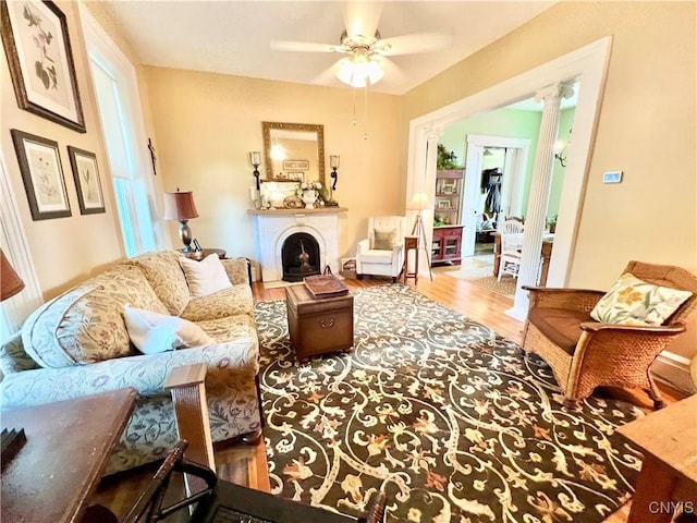 living area featuring a fireplace, a ceiling fan, and wood finished floors