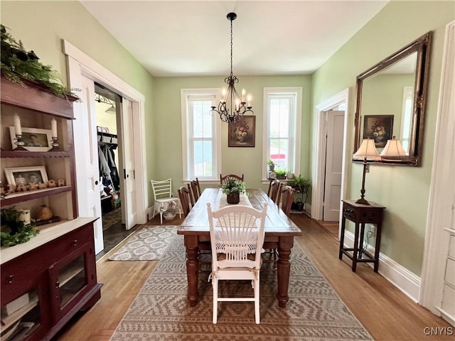 dining area featuring a chandelier, wood finished floors, and baseboards