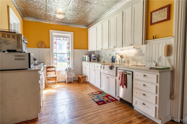 kitchen with light wood-style floors, dishwasher, an ornate ceiling, and a wainscoted wall