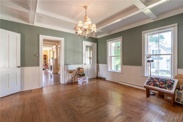 dining area featuring coffered ceiling, a chandelier, and wainscoting