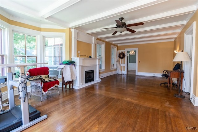 living room with baseboards, a ceiling fan, a fireplace, beamed ceiling, and wood finished floors