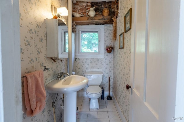 bathroom with toilet, wallpapered walls, baseboards, and tile patterned flooring