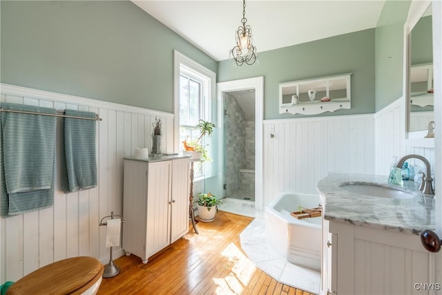 full bathroom with a garden tub, a shower stall, vanity, a wainscoted wall, and wood-type flooring