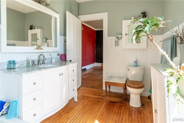 bathroom featuring vanity, a wainscoted wall, toilet, and wood finished floors