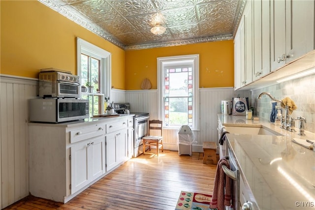 kitchen featuring appliances with stainless steel finishes, wainscoting, and an ornate ceiling