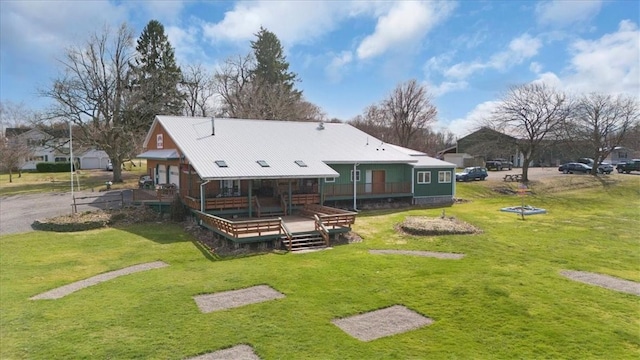 rear view of property with a wooden deck and a lawn
