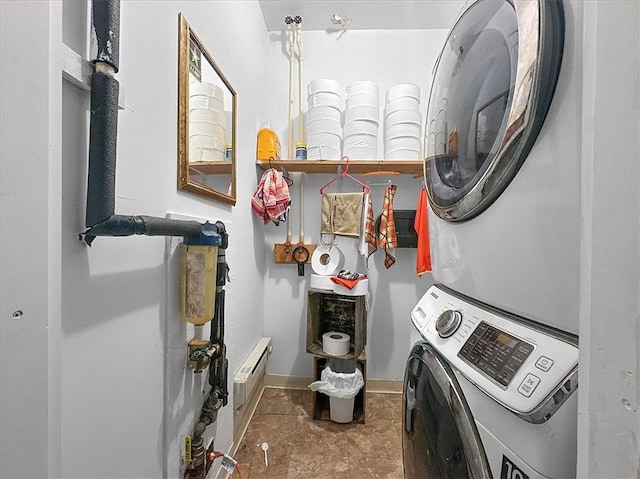 clothes washing area featuring stacked washer / dryer, laundry area, and baseboards