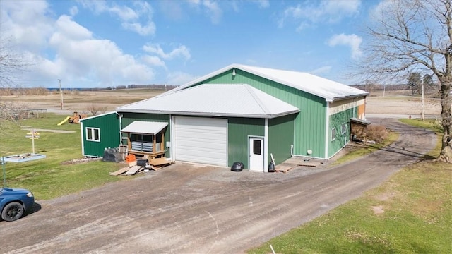 view of pole building featuring dirt driveway and a lawn