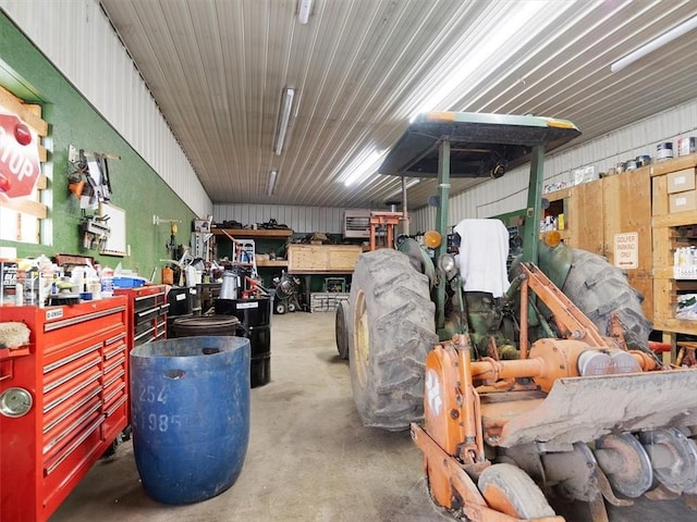 interior space featuring concrete flooring, metal wall, a garage, and a workshop area