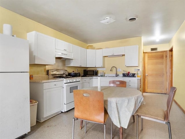 kitchen featuring white cabinets, under cabinet range hood, white appliances, and visible vents