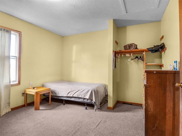 bedroom featuring carpet, attic access, baseboards, and a textured ceiling