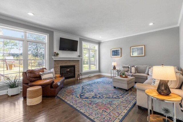 living room featuring a glass covered fireplace, baseboards, ornamental molding, recessed lighting, and wood finished floors