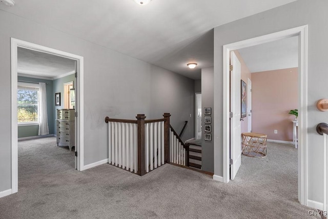 corridor with baseboards, an upstairs landing, and carpet floors