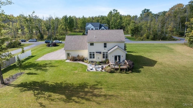 rear view of house with a view of trees, a wooden deck, fence, and a lawn