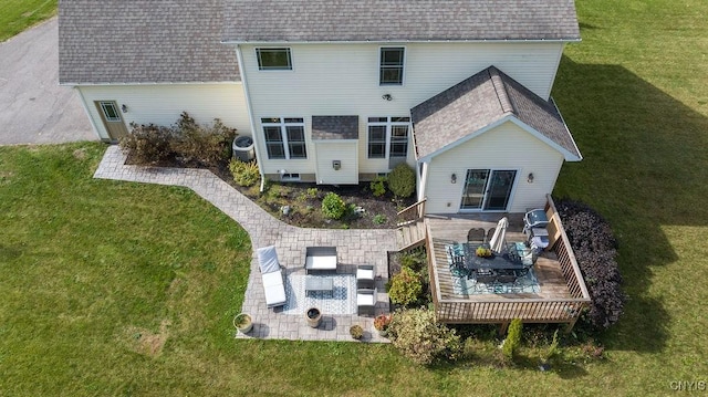rear view of house featuring a yard, a deck, and roof with shingles