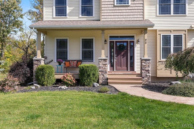 property entrance featuring covered porch, a lawn, and roof with shingles