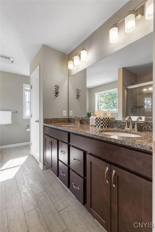 full bath featuring a stall shower, double vanity, a sink, and visible vents