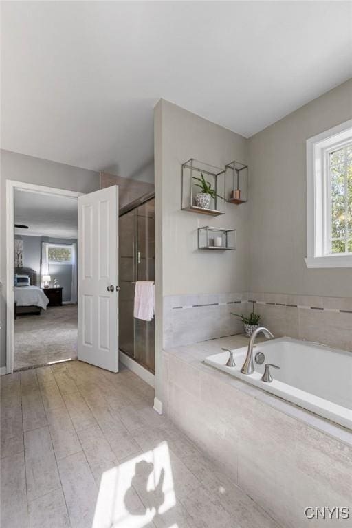 ensuite bathroom with connected bathroom, a garden tub, and a stall shower