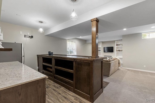 interior space with dark brown cabinetry, baseboards, open floor plan, freestanding refrigerator, and decorative light fixtures