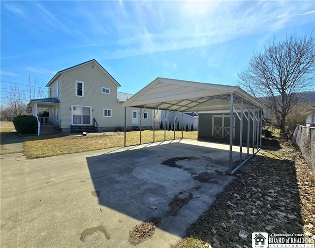 216 S Pleasant St, Shinglehouse, PA 16748 - exterior space with aphalt driveway, a detached carport, fence, and a storage unit