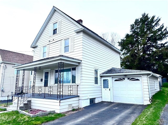 view of front of house with an attached garage, a chimney, covered porch, and aphalt driveway
