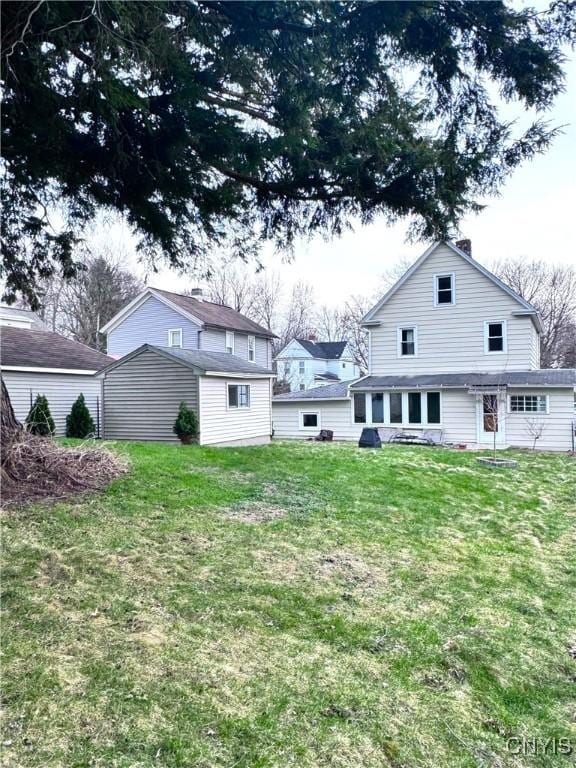back of property featuring an outdoor structure and a lawn