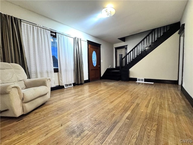 entryway with stairs, visible vents, hardwood / wood-style flooring, and baseboards