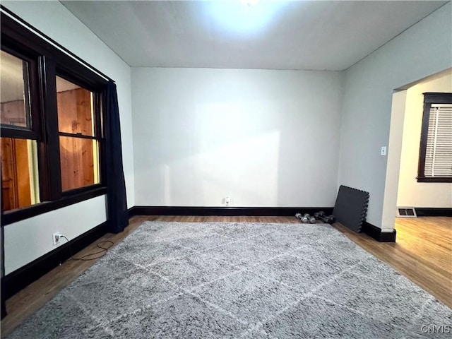 empty room featuring wood finished floors, baseboards, and visible vents