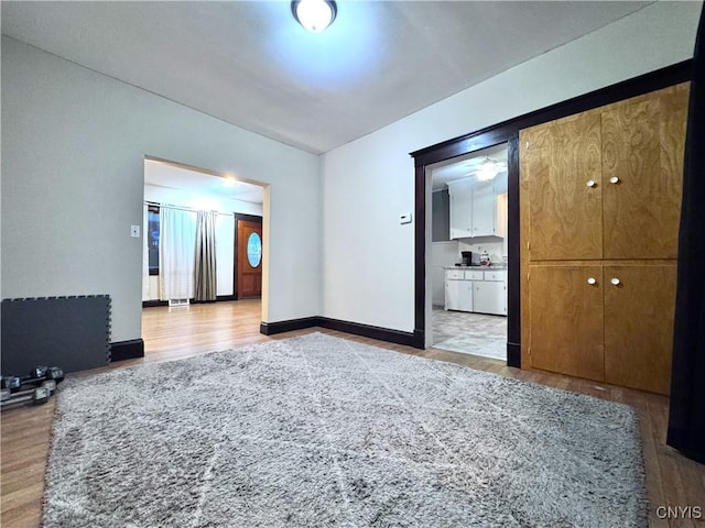 unfurnished bedroom with wood finished floors, ensuite bath, and baseboards