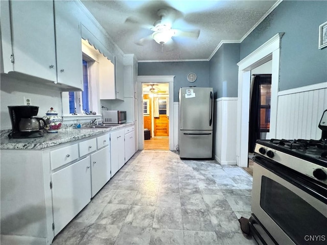 kitchen with crown molding, ceiling fan, appliances with stainless steel finishes, and white cabinets