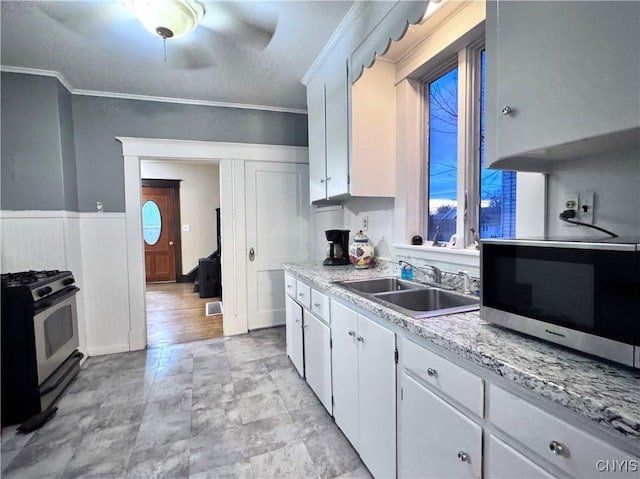 kitchen with a sink, ornamental molding, light countertops, and stainless steel appliances